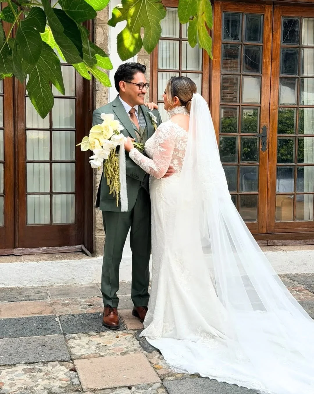 Pareja de recién casados celebrando frente a una fachada con puertas de madera